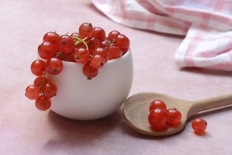 Redcurrants in small bowls and wooden spoon, Ribes rubrum