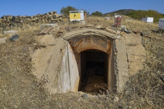 Lost Place, concrete bunker entrance in dry landscape under blue sky with vegetation, Italian air