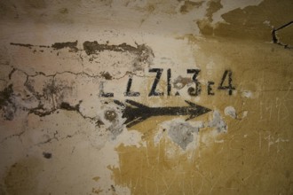 Lost Place, Ruin of a barracks, Patched wall with arrows and numbers in black on yellow, weathered