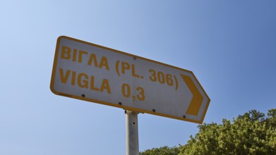 Directional sign in Greek and English under blue sky, Italian air defence position, ground defence