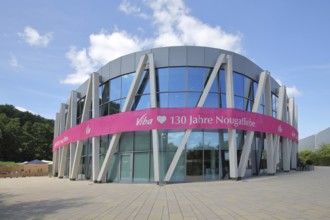 Modern round building with glass window and pink banner with inscription, anniversary 130 years of