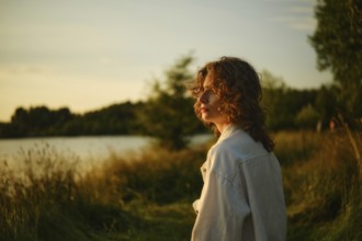 On a bright, hot day at the lake, a young person stands beside the water, absorbed in the stunning