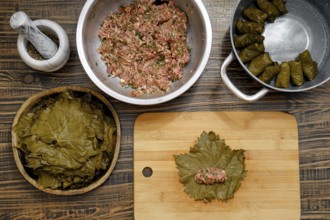 In a cozy kitchen, grape leaves are prepared for making dolma. A mixture of rice and minced meat is