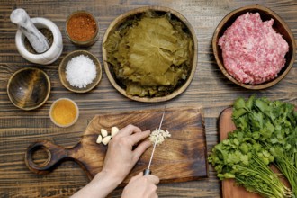 Preparing dolma at home involves chopping garlic and herbs while surrounded by fresh grape leaves