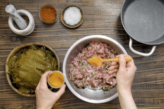 Preparing dolma involves mixing ground meat with herbs and spices before rolling it in grape leaves