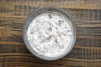 Overhead view of a bowl with sour cream mixed with chopped parsley, cilantro and garlik. Classic