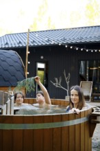 Two children and their mother playfully enjoy an outdoor hot tub at a charming cabin