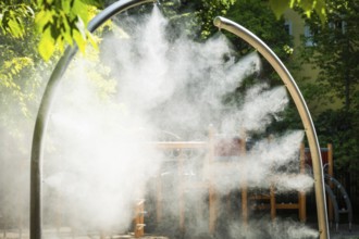 A mobile spray arch sprays fine water mist in a park in Bratislava, Slovakia