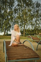 A woman sits comfortably on a lounge chair at the beach as the warm sunlight illuminates her