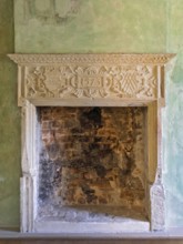 Artfully carved stone fireplace in green antique surroundings with exposed bricks, Lüdinghausen