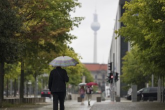 People walk with umbrellas through the government district in Berlin, 21.07.2025