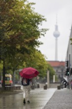 People walk with umbrellas through the government district in Berlin, 21.07.2025