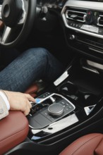 At a modern vehicle a driver is adjusting the control panel while seated comfortably