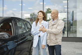 A couple is happily engaged in a conversation while selecting a new car at a dealership. The woman
