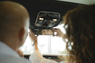 The view from the rear seat of the car is a couple of sitting in front. A woman sets up a rear view