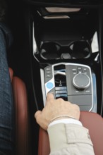 A driver is adjusting the controls in a luxury vehicle. The focus is on the comfortable leather