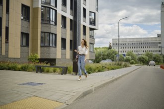 Woman strolling along the street in urban area with modern architecture on a cloudy afternoon