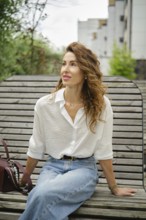Woman sitting on a bench in a park, enjoying her surroundings during a sunny afternoon