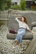 A woman enjoys her time on a stylish bench in a contemporary outdoor area filled with greenery. She