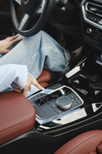 A person sits comfortably in a modern car, pressing buttons on the console with a stylish design.