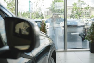 A customer stands outside a car dealership, looking at various vehicles through glass windows, AI