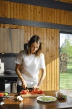 A woman is chopping fresh bell pepper in a rustic kitchen. Sunlight pours through the window,
