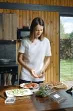 A woman lays slices of salmon on a tortilla with cream cheese and herbs. She cooks a quick and