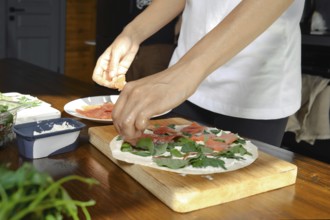 A person is preparing a healthy dish in a cozy kitchen setting. Fresh greens, slices of salmon, and