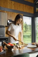 Preparing healthy dishes with fresh ingredients in a sunlit kitchen surrounded by nature