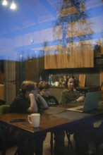 A cozy setting captures two children and an adult focused on a laptop screen inside a modern home.