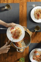 Close-up view of female hands serving pasta with stir fry spicy beef with vegetables on a plate