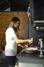 A woman prepares a healthy vegetarian dish in a charming kitchen. Bright vegetables are being added