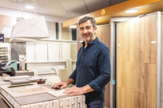 Smiling architect choosing material samples in a home improvement store, he is touching ceramic and