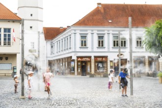 Water mist system in the city centre of Trencin, children use the refreshment in the summer heat,