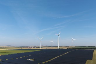 Fields full of solar panels with several wind turbines under a cloudless sky, near Kitzingen, Lower