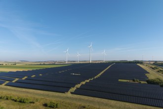 Large-scale solar panels and wind turbines across a wide agricultural field, near Kitzingen, Lower
