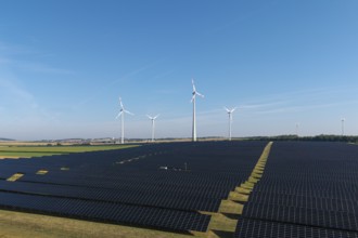 Solar panels and wind turbines on a wide field under a clear sky, near Kitzingen, Lower Franconia,