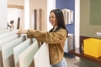 Smiling woman selecting ceramic tiles in a home improvement store, planning a bathroom renovation