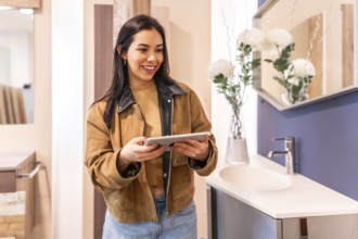 Smiling woman using a digital tablet while choosing a new bathroom sink in a home improvement store