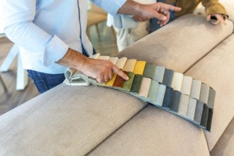 Interior designer showing fabric swatches to client, choosing upholstery for new sofa in furniture