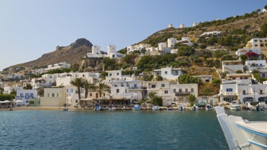 Coastal town with white houses on the hillside and a lively harbour in front of a blue sea,