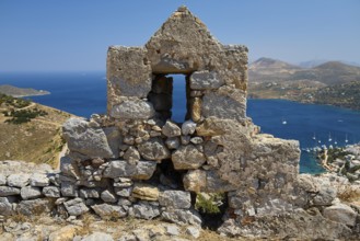 Stone ruin with window, sea and mountain landscape in the background under blue sky, Pandeli