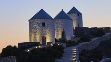 Illuminated windmills in the twilight on a stony hill, Pandeli Castle, castle, Leros fortress, St
