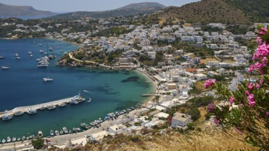 View of a Greek coastal town with flowers and yachts surrounded by blue sea, Pandeli Castle,