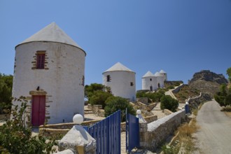 White windmills with red doors along a path under a clear sky on an island, Pandeli Castle, Castle,