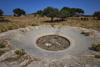 Concrete crater in an arid landscape with scattered trees under a blue sky, Lost Place, Air Defence