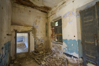 Lost Place, Dilapidated interior with rubble and crumbling walls, windows and old doors visible,