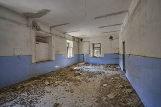 Lost Place, Abandoned room covered with rubble, blue wall plaster and damaged ceiling visible,