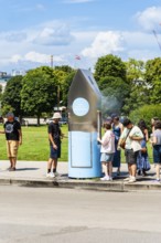 A queue of people in front of a drinking water fountain in the city centre of Vienna, Austria