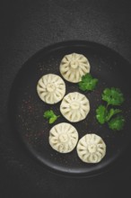 Khinkali, a traditional Georgian dish, with spices and herbs, top view, no people, on a black plate